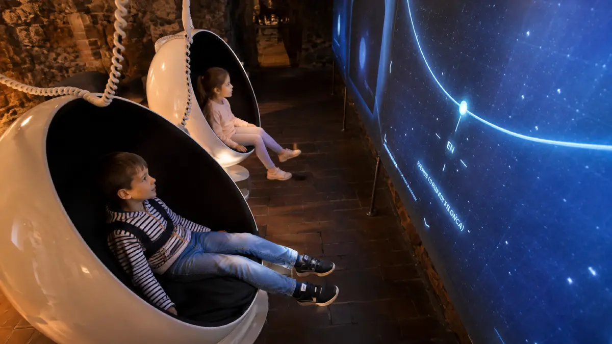 Dzieci w fotelach multimedialnych przed ekranem astronomicznym