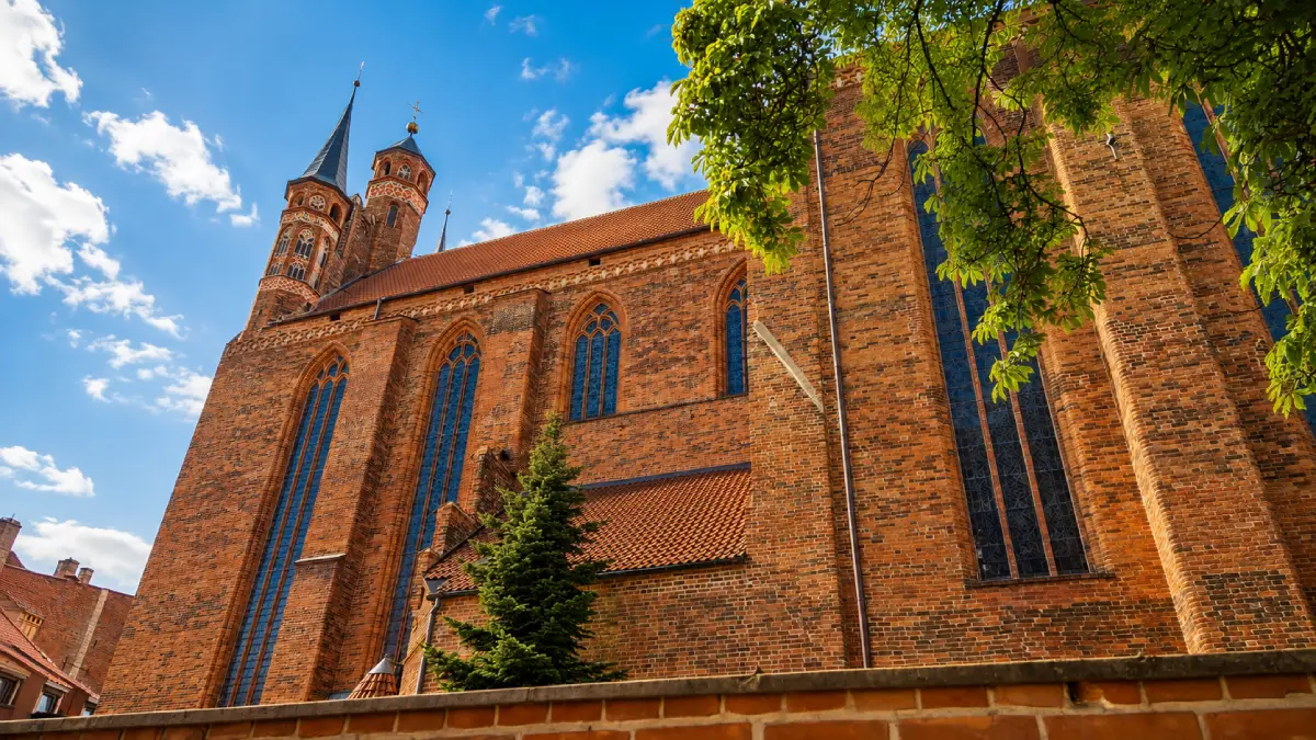 Widok na ceglane mury i prezbiterium Kościoła Mariackiego w Toruniu od ulicy