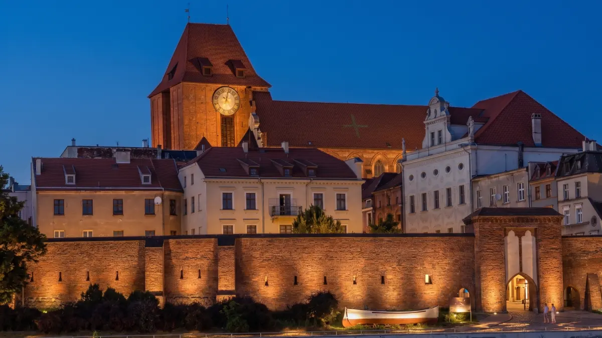 Iluminowane mury obronne w Toruniu wieczorem